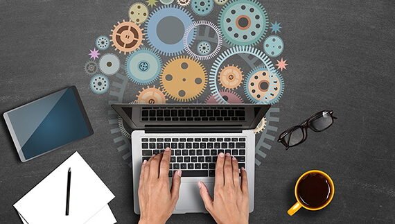 High angle view of a businessman hands using laptop with gears. Concepts of collaboration and progress.